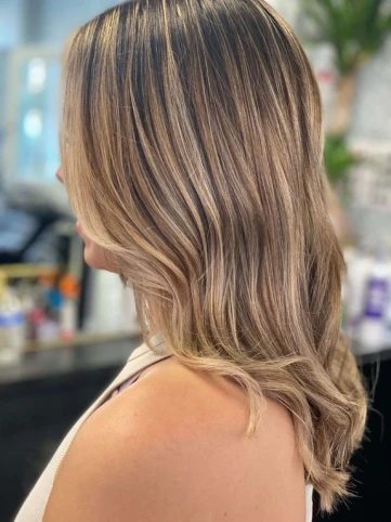 A woman with freshly styled blonde balayage hair